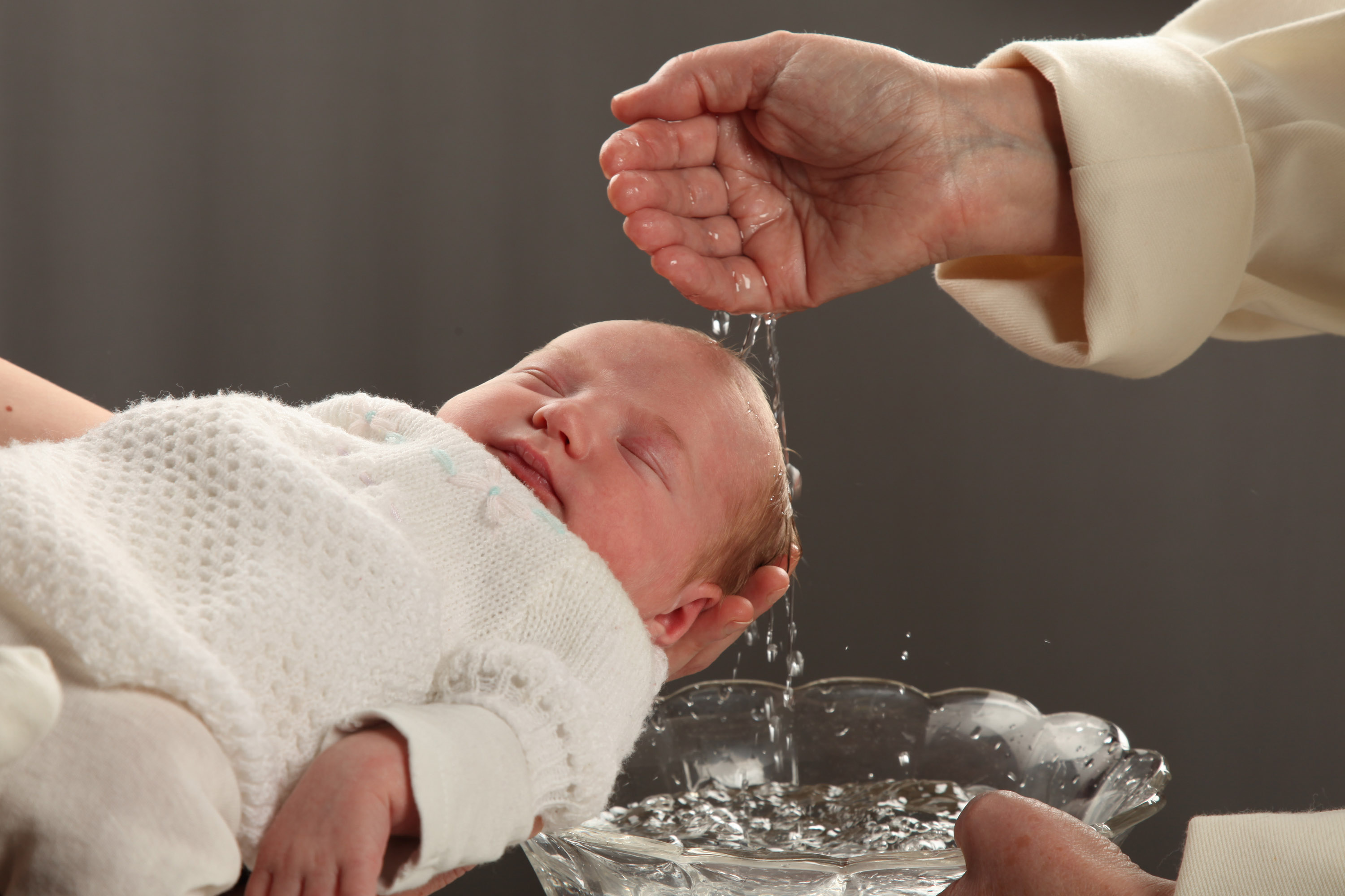 Pappi kastaa pientä lasta.